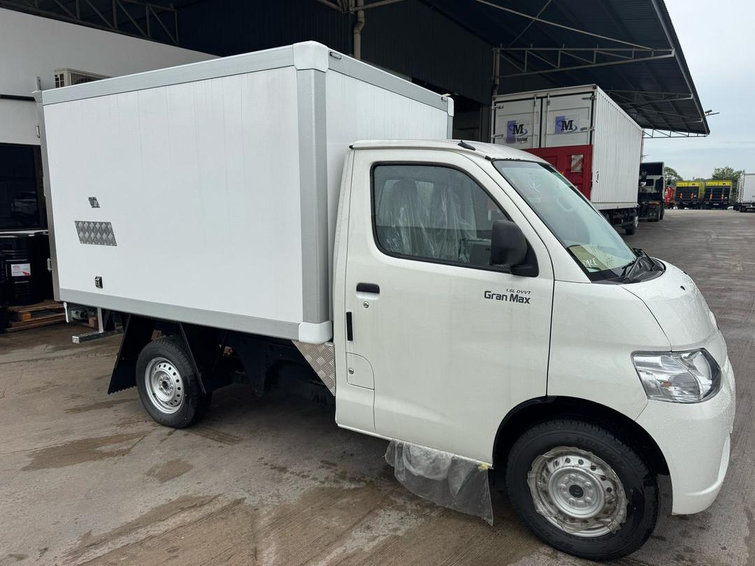 A white 2026 Daihatsu Gran Max box truck cab with a large white cargo body, photographed outdoors in a warehouse or lot. The side door shows the text 'Gran Max'.