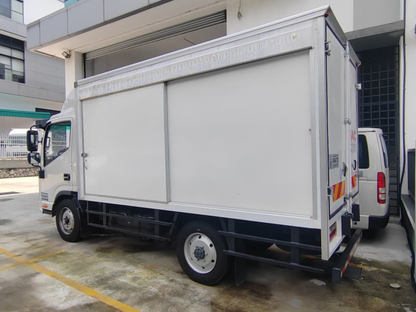 A white JAC N50 box bonded truck parked outdoors in a lot next to a building, with a second white vehicle partially visible behind it.